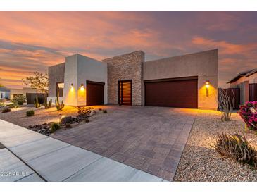 Modern home showcasing a stone facade, desert landscaping, and a stylish paver driveway at sunset at 1330 E Monte Way, Phoenix, AZ 85042