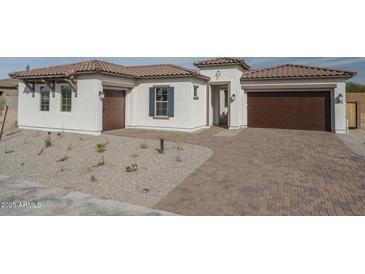 Charming single-story home with a desert-scape front yard, a brick driveway, and a two-car garage at 18564 W Cathedral Rock Dr, Goodyear, AZ 85338