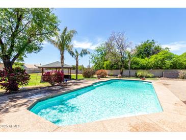 Refreshing in-ground pool surrounded by lush greenery and mature trees with a covered gazebo in the backyard at 2043 E Quartz St, Mesa, AZ 85213