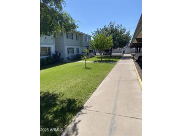 Exterior of condo with sidewalk, green grass and shade trees at 2569 W Berridge Ln # D-115, Phoenix, AZ 85017