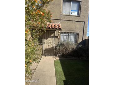 Charming home exterior featuring a secure gated entrance with decorative tile roof accent at 4628 E Wood St, Phoenix, AZ 85040