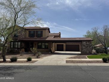 Charming two-story home with a tiled roof and stone accents on a well-maintained landscaped lot and three-car garage at 21405 W Brittle Bush Ln, Buckeye, AZ 85396
