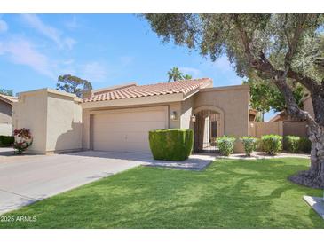 Charming single-story home featuring a well-manicured lawn, mature trees, and a tile roof at 2663 N Carriage Ln, Chandler, AZ 85224