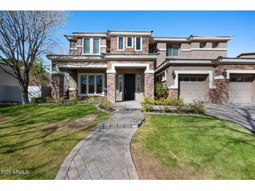 Inviting two-story home with stone accents, manicured lawn, and three-car garage, blending elegance and practicality at 2988 E Comstock Dr, Gilbert, AZ 85296