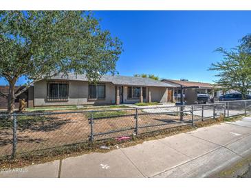 Modest single-story home with a chain link fence and desert landscaping in need of renovation at 4870 W Almeria Rd, Phoenix, AZ 85035