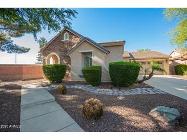 Charming home featuring a stone facade, manicured bushes, and a well-maintained yard at 15272 W Georgia Dr, Surprise, AZ 85379