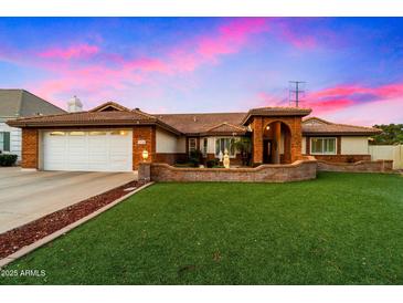 Charming brick home featuring a lush lawn, arched entryway and white garage door at 1934 E Cypress Tree Dr, Gilbert, AZ 85234