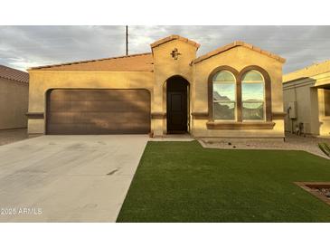 Charming single-story home featuring a two-car garage, well-maintained lawn, and inviting arched windows at 29109 N Fire Agate Rd, San Tan Valley, AZ 85143