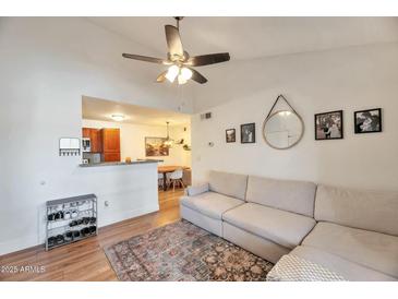 Cozy living room with hardwood floors, ceiling fan, and comfortable seating; adjacent to a modern kitchen and dining area at 623 W Guadalupe Rd # 213, Mesa, AZ 85210