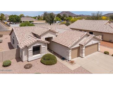 Beige single-story home featuring a tile roof, desert landscaping, and a two-car garage at 6988 W Monte Lindo --, Glendale, AZ 85310