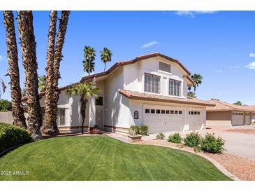 Charming two-story home with a three-car garage, manicured lawn, and beautiful palm trees at 9012 E Sutton Dr, Scottsdale, AZ 85260