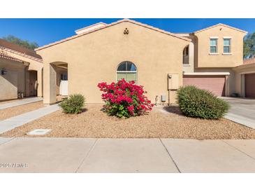 Two-story home featuring charming architecture, a red flower bush and a two car garage at 1367 S Country Club Dr # 1039, Mesa, AZ 85210
