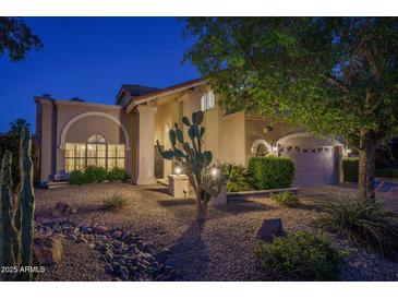 Charming home exterior with desert landscaping, stucco facade, and covered entrance at dusk at 19115 N 71St Dr, Glendale, AZ 85308