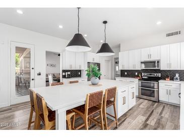 Bright, modern kitchen with stainless steel appliances, breakfast bar and eat-in dining space at 7236 W Aurora Dr, Glendale, AZ 85308