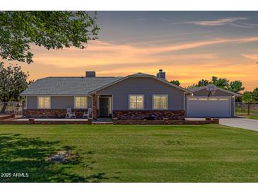 Charming single-story home with a brick foundation, well-manicured lawn, and a detached garage at sunset at 1551 E Longhorn Dr, Chandler, AZ 85286