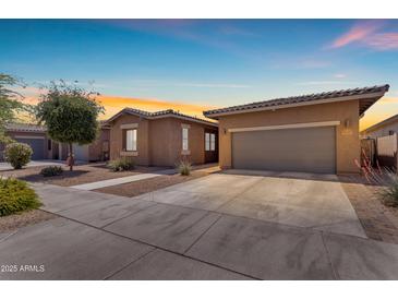 Charming single-story home with a well-maintained lawn and two-car garage at sunset at 22977 E Desert Spoon Dr, Queen Creek, AZ 85142
