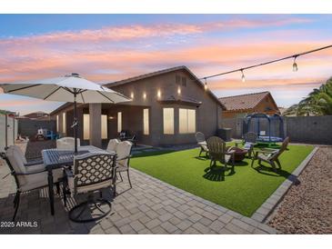 A well-kept backyard with green synthetic lawn, patio furniture set, and outdoor entertaining area at 2768 W Jasper Butte Dr, San Tan Valley, AZ 85144