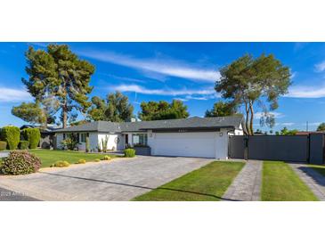 Beautiful single-story home featuring a lush lawn, desert landscaping, and a private gated entrance at 3027 W Wescott Dr, Phoenix, AZ 85027