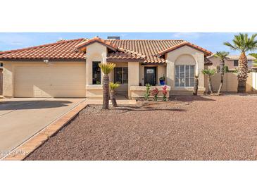 Charming single-story home featuring a tile roof, desert landscaping, and a two-car garage at 7108 W Corrine Dr, Peoria, AZ 85381