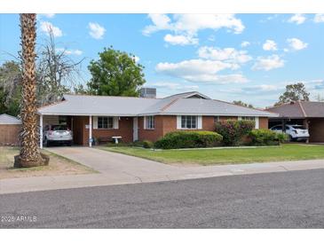 Charming brick home featuring a well-manicured lawn and mature landscaping at 3616 E Fairmount Ave, Phoenix, AZ 85018