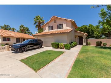 Charming two-story home with a well-manicured lawn and mature trees at 7512 W Tonto Dr, Glendale, AZ 85308