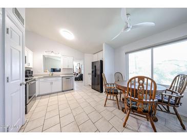 Eat-in kitchen features white cabinets, stainless steel appliances, tile floors, and a four-chair dining table at 8521 W Mauna Loa Ln, Peoria, AZ 85381
