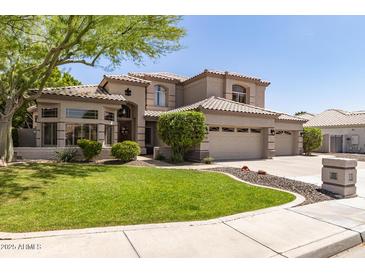 Charming two-story home boasts a lush green lawn, mature trees, and a three-car garage at 1181 N Dustin Ln, Chandler, AZ 85226