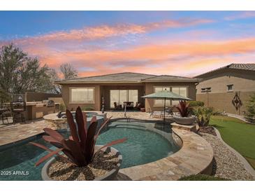 A stunning backyard oasis showcasing a private pool, spa, built-in BBQ, and desert landscaping at 12381 S 182Nd Dr, Goodyear, AZ 85338