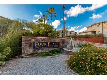 Stone sign for Four Peaks Condominium Homes with plants, blue sky, palm trees, and fountains create an inviting entrance at 13700 N Fountain Hills Blvd # 155, Fountain Hills, AZ 85268