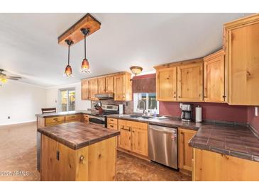 Well-lit kitchen featuring wood cabinets, stainless steel appliances, and a tiled center island at 17913 E Watford Dr, Queen Creek, AZ 85142