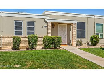Inviting front entrance with well-maintained lawn and shrubbery leading to the front door at 10072 W Lancaster Dr, Sun City, AZ 85351