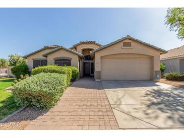 Charming single-story home with a well-manicured front yard, a brick walkway, and a two-car garage at 16605 W Pierce St, Goodyear, AZ 85338