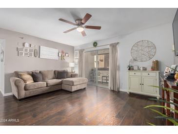 Cozy living room features hardwood floors, ceiling fan, and sliding glass doors to the patio at 4554 E Paradise Village Pkwy # 267, Phoenix, AZ 85032