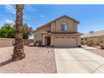 Two-story home featuring a two-car garage, gravel landscaping, and a unique palm tree in the front yard at 6657 W Aurora Dr, Glendale, AZ 85308
