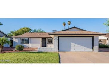 Charming single-story home with a well-maintained lawn, a two-car garage, and mature trees at 8716 E Mitchell Dr, Scottsdale, AZ 85251