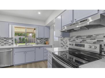 Updated kitchen with stainless steel appliances, stylish tile backsplash, and quartz countertops at 9911 W Pleasant Valley Rd, Sun City, AZ 85351