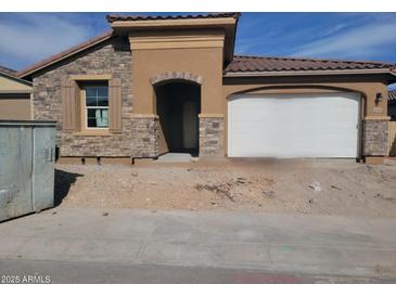 Charming single-story home showcasing a stone facade, arched entryway, and two-car garage with a neutral color scheme at 31453 N 130Th Ave, Peoria, AZ 85383