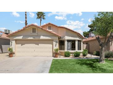 Charming single-story home with a two-car garage, manicured lawn, and a lovely bay window at 4420 E Amberwood Dr, Phoenix, AZ 85048