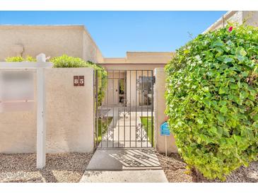 Inviting home featuring a secure, wrought-iron gate, private courtyard, and lush, mature landscaping at 4525 N 66Th St # 85, Scottsdale, AZ 85251