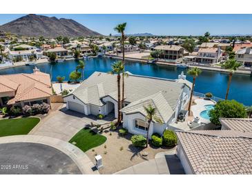 Stunning waterfront home featuring a private pool, lush landscaping, and a three-car garage at 21663 N 57Th Ave, Glendale, AZ 85308