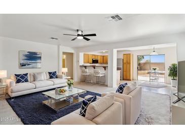Bright living room boasts white sofas, a modern coffee table, and an open floor plan to the kitchen at 25087 W Dove Gap Dr, Buckeye, AZ 85326