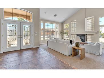 Bright living room featuring soaring ceilings, large windows, tile entry, fireplace, and comfortable seating at 7524 E Leland Cir, Mesa, AZ 85207