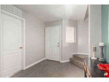 Inviting entryway with tile flooring and a white front door, leading to carpeted stairs at 11473 W Austin Thomas Dr, Surprise, AZ 85378
