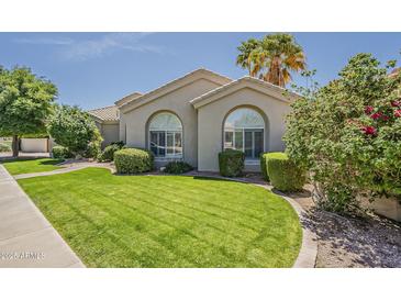 Well-manicured front yard with lush green lawn and mature landscaping creates inviting curb appeal at 11675 E Caron St, Scottsdale, AZ 85259
