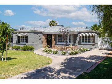 Charming home showcasing a landscaped front yard, stone accents, and black and white striped awnings at 338 W Encanto Blvd, Phoenix, AZ 85003