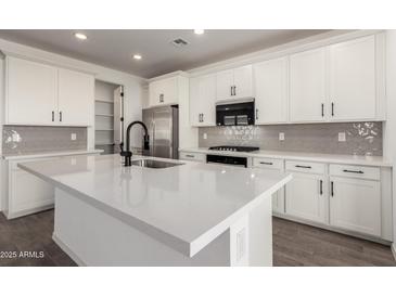 Modern kitchen featuring white cabinets, stainless steel appliances, and a large center island with a white countertop at 4034 W Nora Dr, San Tan Valley, AZ 85144