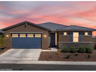 Charming single-story home with a blue garage door, stone accents, and desert landscaping at sunset at 41800 W Sonoran Trl, Maricopa, AZ 85138
