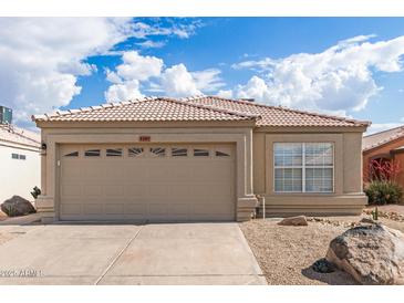 Charming home featuring a tile roof, tan stucco, a 2-car garage, and desert landscaping for low maintenance appeal at 4387 E Hartford Ave, Phoenix, AZ 85032
