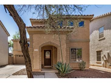 Charming two-story home featuring an arched entryway, tile roof, and desert landscaping at 514 N 112Th Dr, Avondale, AZ 85323