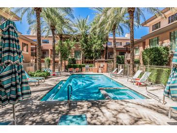 Community pool and spa surrounded by palm trees and lounge chairs in a resort-style setting at 6940 E Cochise Rd # 1027, Paradise Valley, AZ 85253